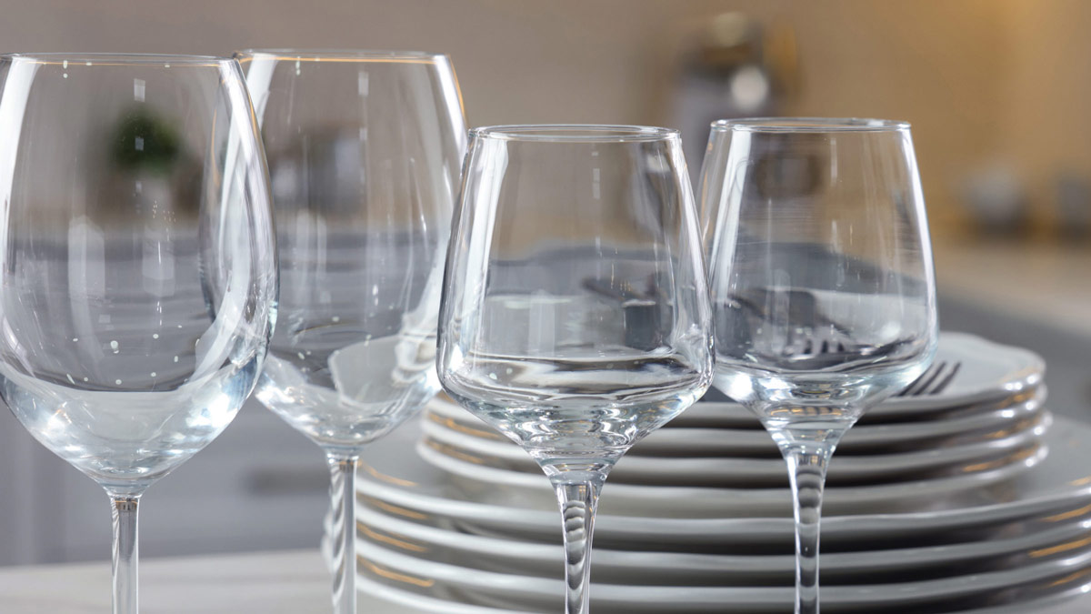 sparkling clean wine glasses in front of a stack of plates