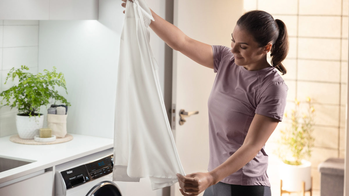 A woman folding a dress shirt in her laundry room